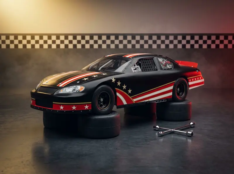 Concept illustration: a 1:24 stock car diecast in a plain black livery with red and white stripes and gold stars, parked on a stack of racing tires with a lug wrench beside it.
